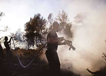 Israeli firefighters douse a burning area in the village of Ussafiya in Carmel forest. AFP photo